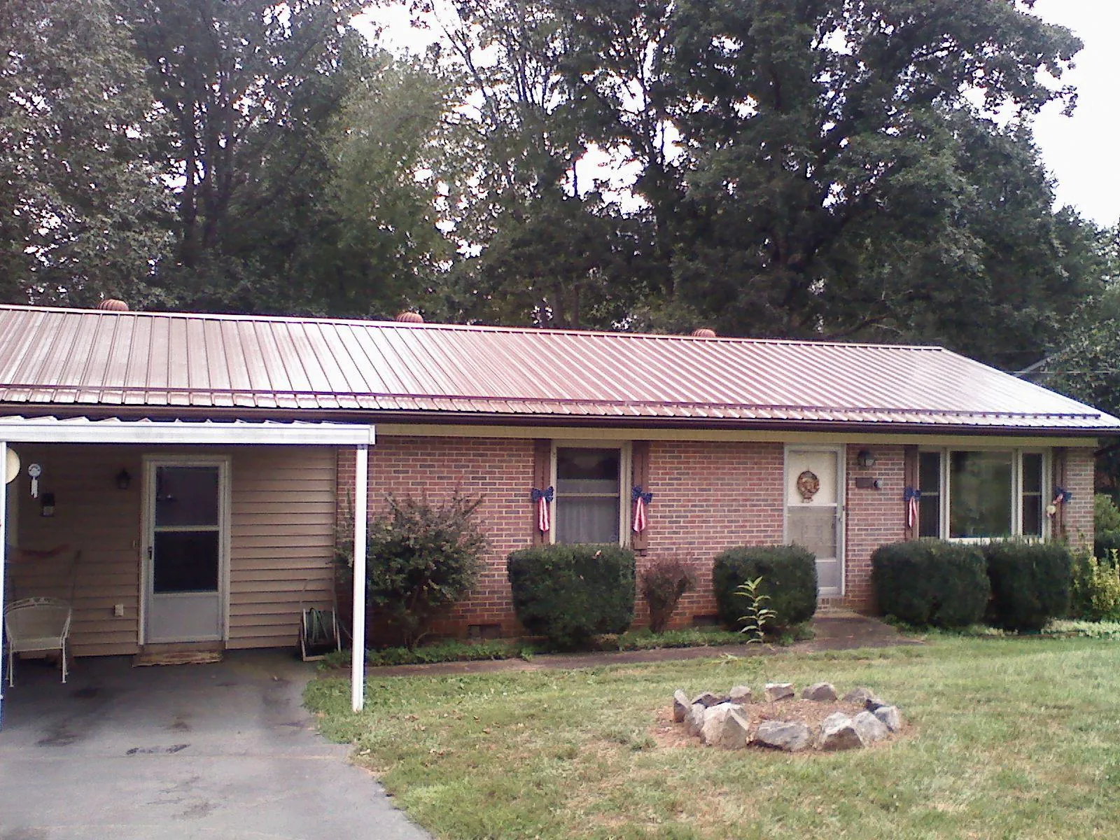 Bronze metal roof and carport on a brick ranch home — Roof Repair work by our crew in Stanley